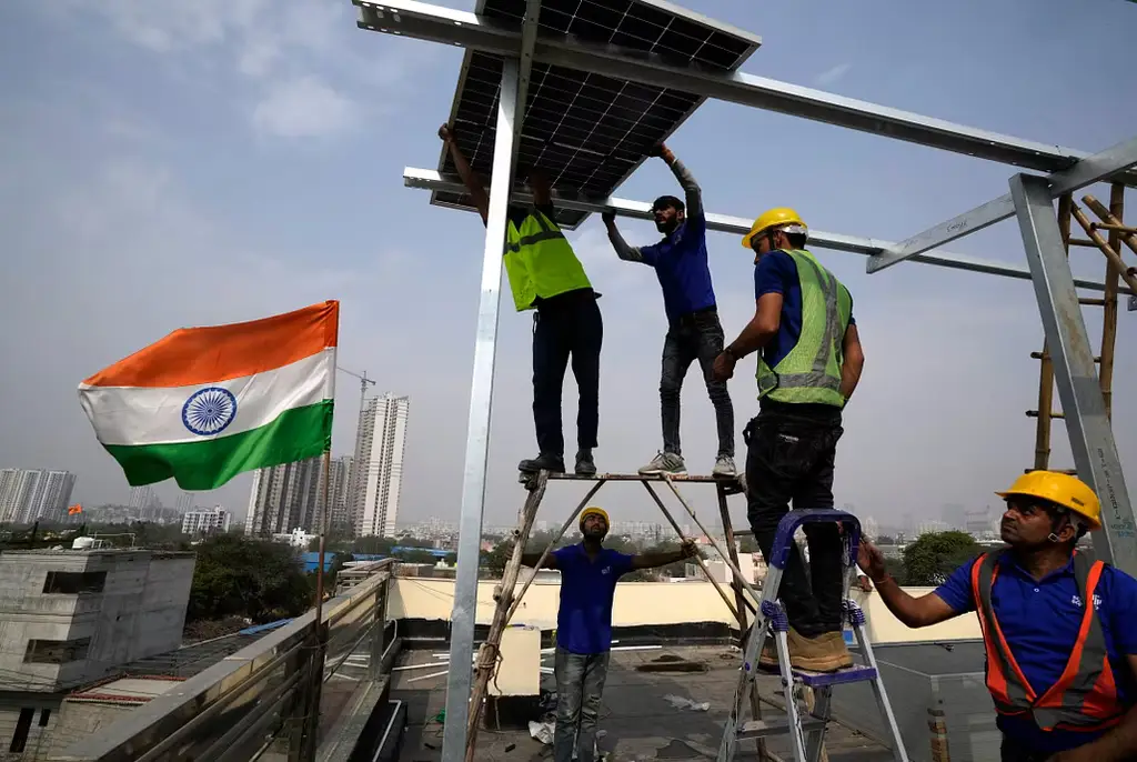 Arbetare placerar en solpanel på taket av ett bostadshus i Gurugram, i utkanten av New Delhi.