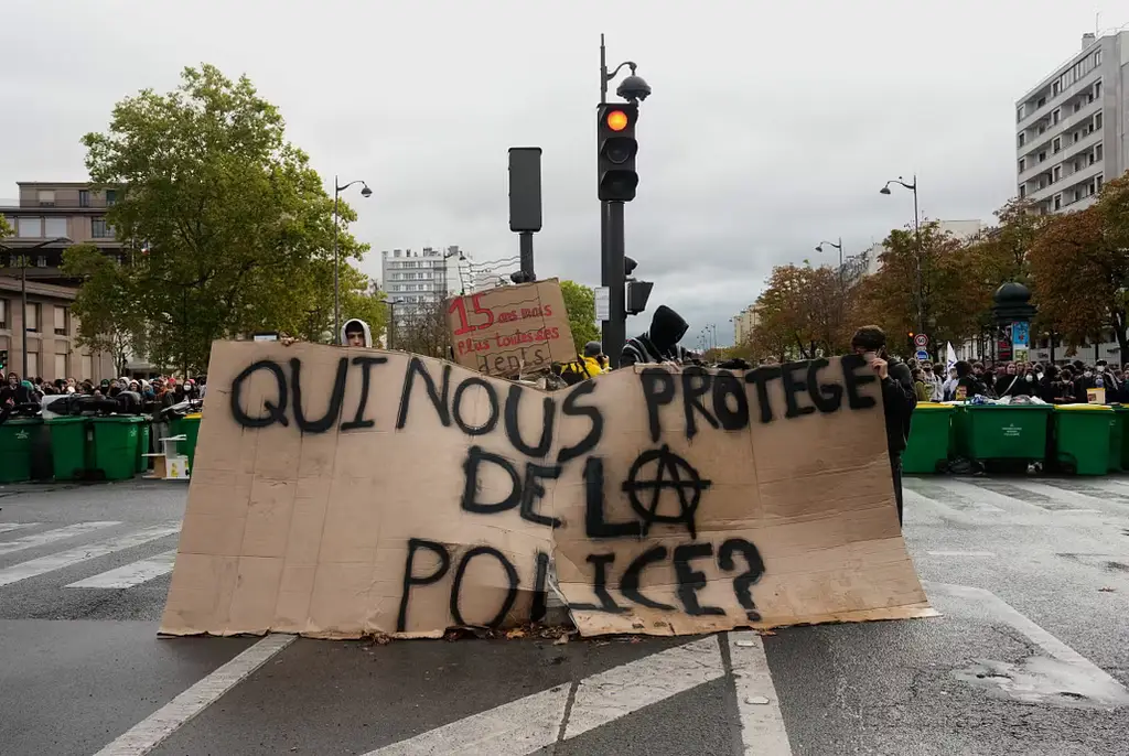 Elever står bakom ett plakat med orden ”Vem skyddar oss från polisen?”.