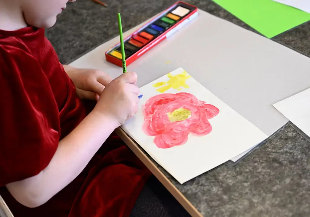 Arkivbild: Barn målar blommor på en förskola. 