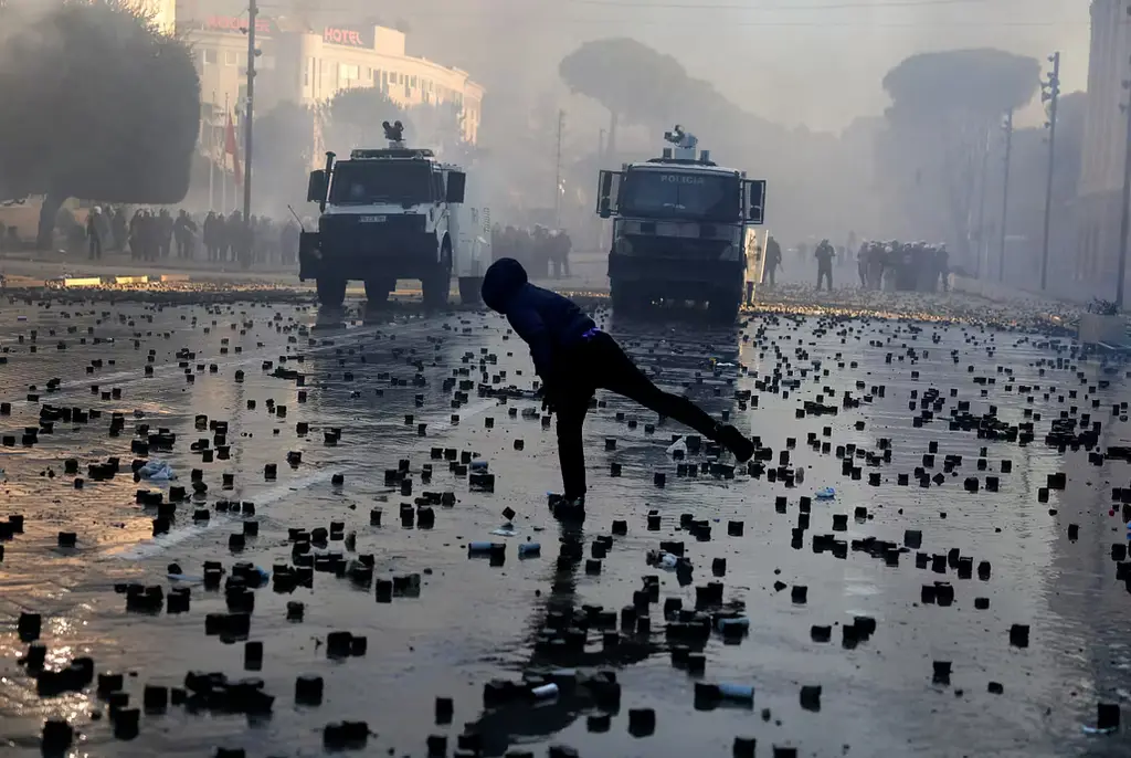 En demonstrant kastar gatsten mot polis i Tirana under lördagen.